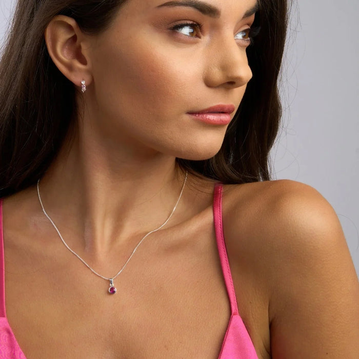 Gold birthstone necklace with a red stone pendant.